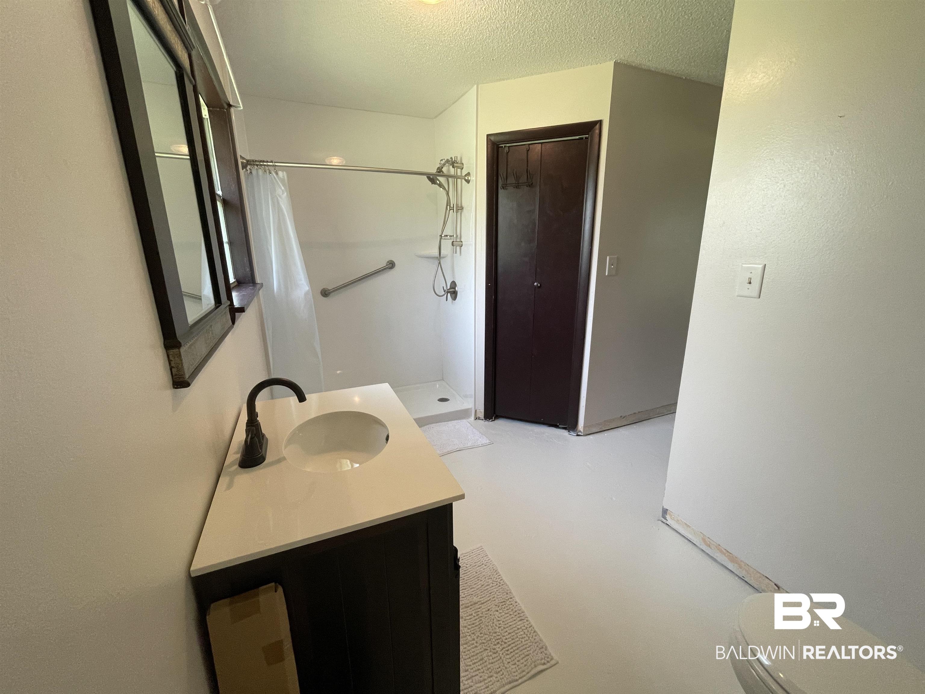 739 Smithfield Road Atmore, AL 36502 - Photo 7 of 18 Bathroom featuring a textured ceiling, concrete floors, toilet, vanity, and curtained shower