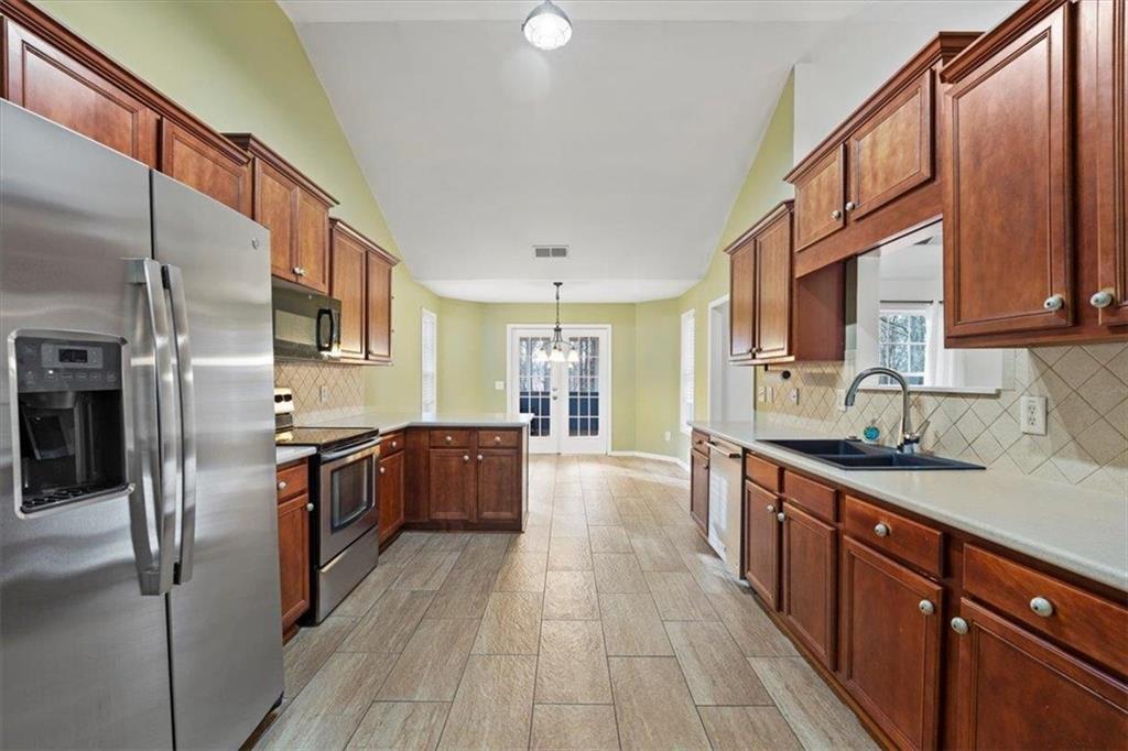 1218 Morgans Run Monroe, GA 30656 - Photo 4 of 39 a large kitchen with stainless steel appliances granite countertop a refrigerator a sink dishwasher a stove and white countertops with wooden floor