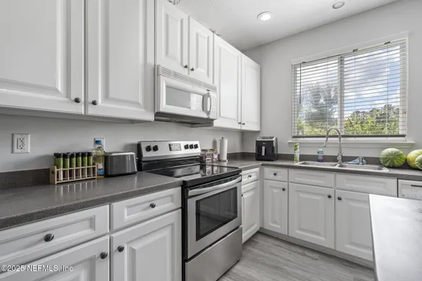 a kitchen with stainless steel appliances granite countertop a sink a stove and cabinets