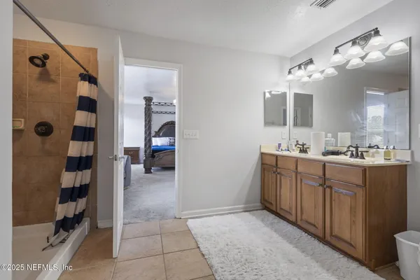 a bathroom with a double vanity sink a toilet a shower and a mirror