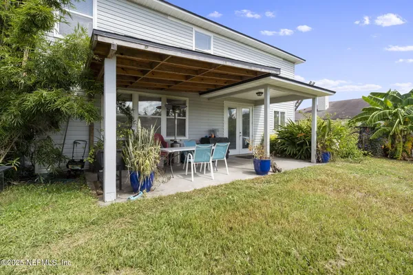 a view of a patio with table and chairs potted plants and floor to ceiling window