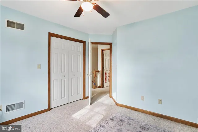 an empty room with closet and a chandelier fan