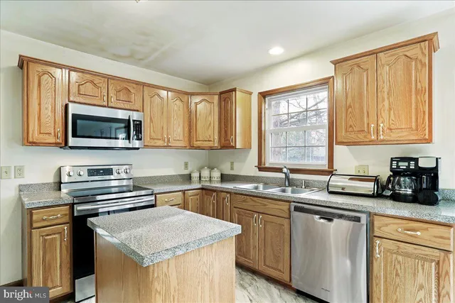 a kitchen with stainless steel appliances granite countertop a sink stove microwave and refrigerator