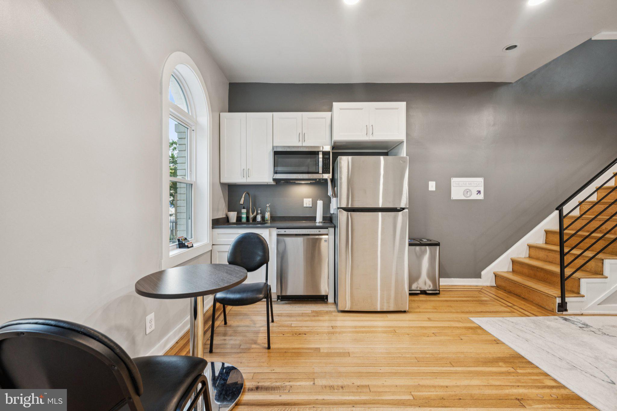 2708 Ontario Road Northwest Washington, DC 20009 - Photo 7 of 31 a kitchen with stainless steel appliances granite countertop a refrigerator a stove a sink and a dining table with wooden floor