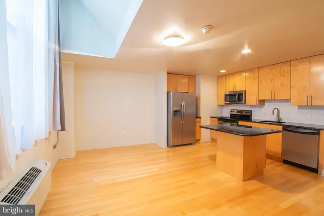 a kitchen with stainless steel appliances granite countertop a refrigerator a stove a sink and a microwave