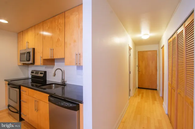 a kitchen with stainless steel appliances a sink a stove a refrigerator a microwave oven and cabinets