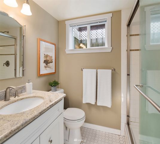 a bathroom with a granite countertop sink mirror vanity and toilet