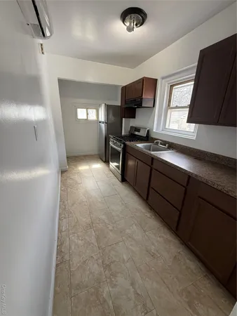 a kitchen with stainless steel appliances granite countertop a sink a stove top oven a chimney and a refrigerator