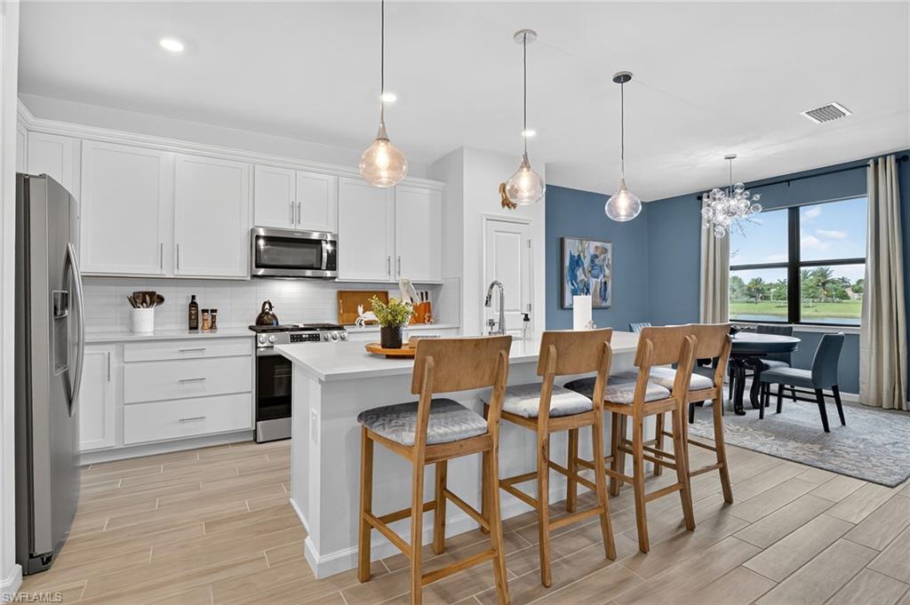 1657 Serena Avenue Naples, FL 34120 - Photo 10 of 40 a kitchen with stainless steel appliances kitchen island granite countertop a table chairs and a refrigerator