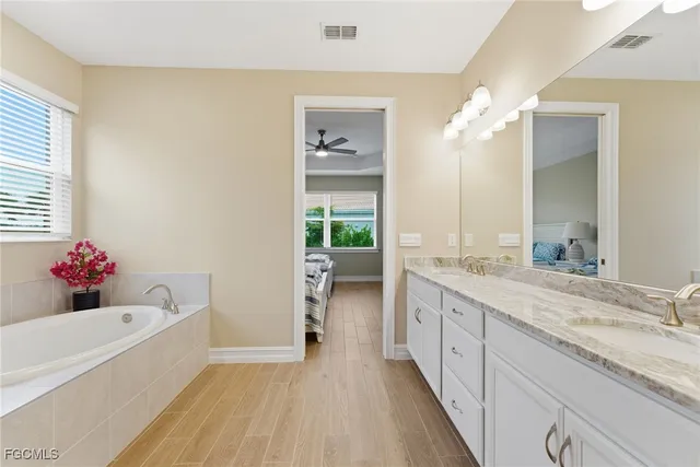 a bathroom with a granite countertop double vanity sink a mirror and a bathtub