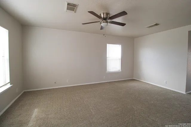 an empty room with a window and a fan
