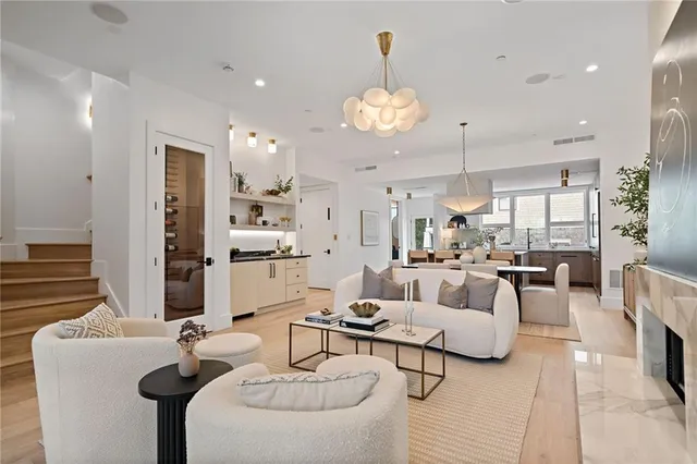 a living room with furniture kitchen view and a chandelier