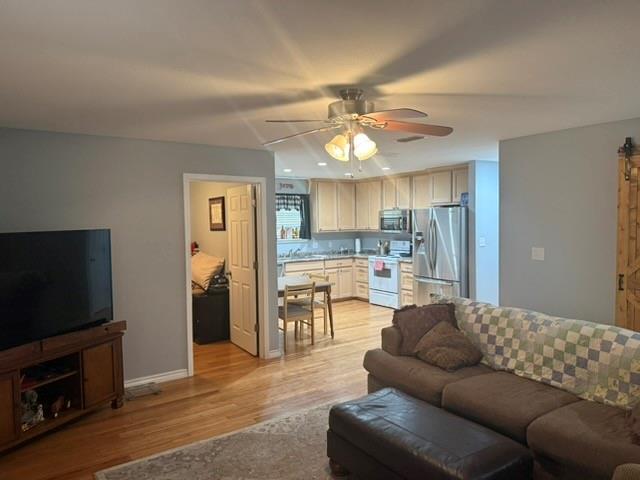 1387 Hickory Street Rhome, TX 76078 - Photo 29 of 36 Barndominium - Living room transitioning to kitchen featuring light wood-finish cabinetry, granite-style countertops, stainless steel appliances, and wood-finish flooring.