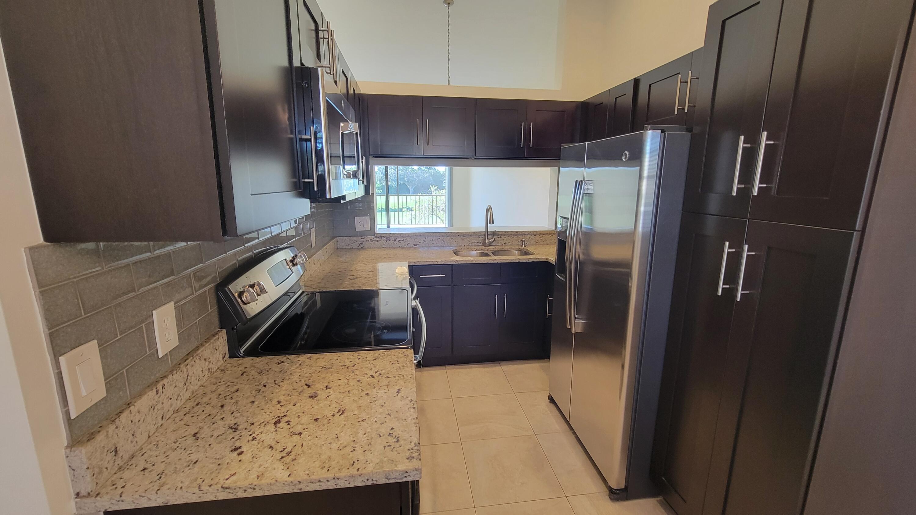 1072 Keystone Drive, Unit A Jupiter, FL 33458 - Photo 11 of 29 a kitchen with a sink a refrigerator and cabinets