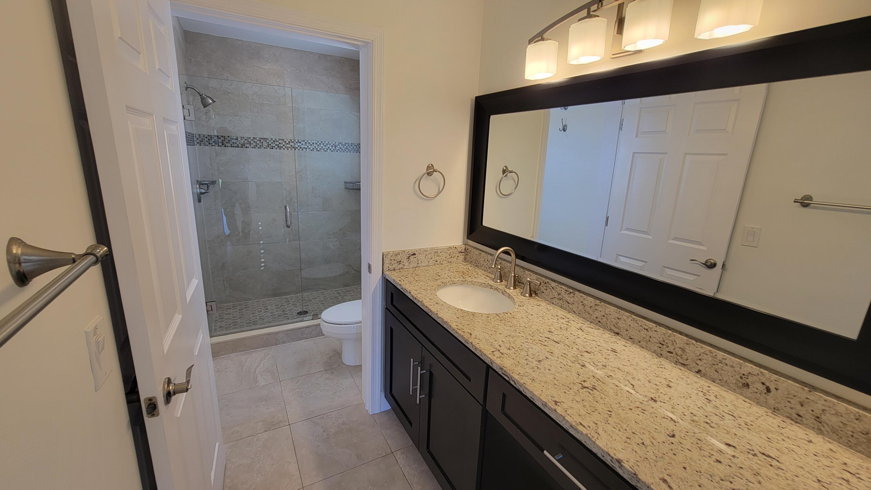 1072 Keystone Drive, Unit A Jupiter, FL 33458 - Photo 16 of 29 a bathroom with a granite countertop sink toilet and shower