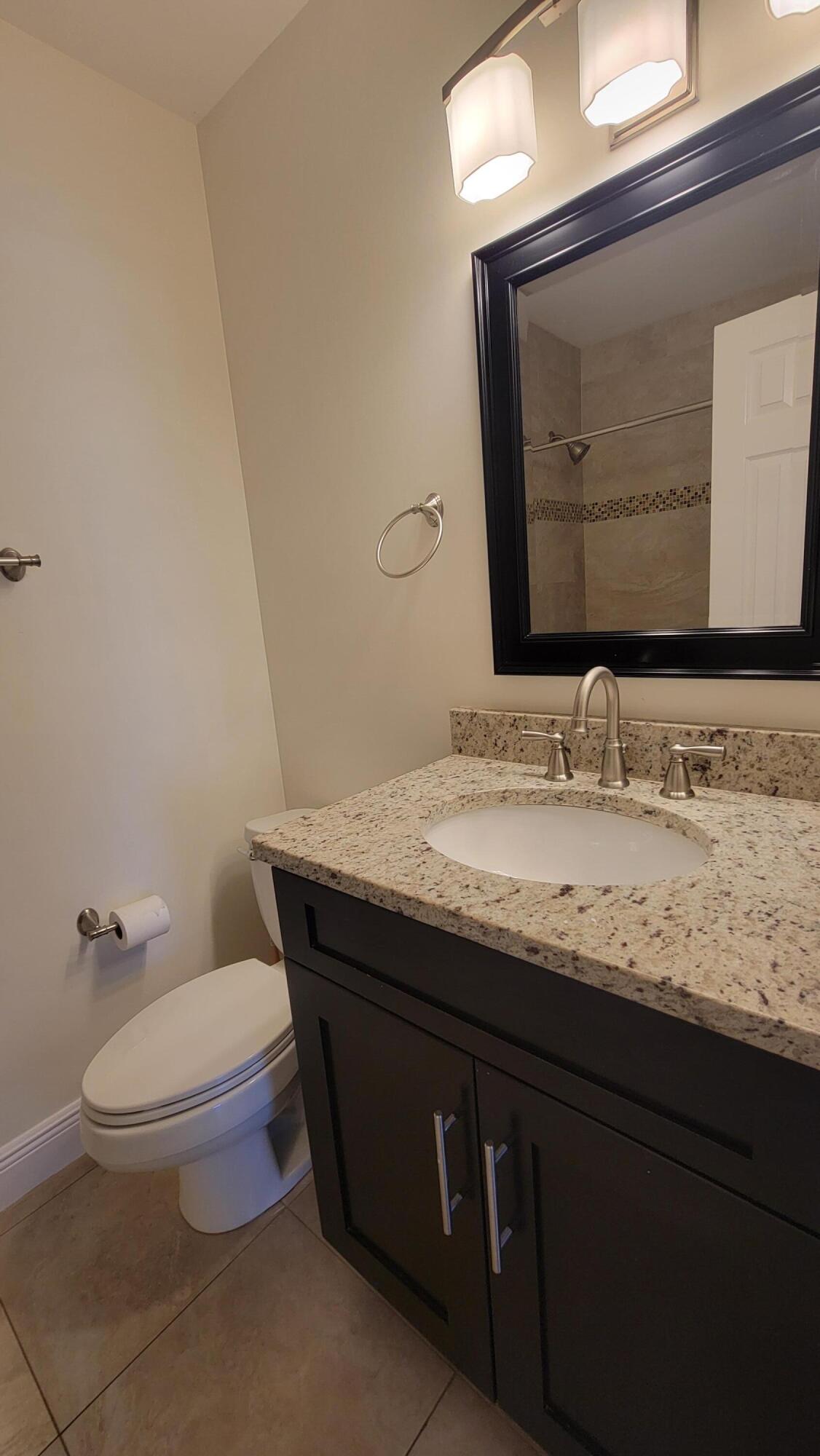 1072 Keystone Drive, Unit A Jupiter, FL 33458 - Photo 20 of 29 a bathroom with a granite countertop toilet sink and mirror
