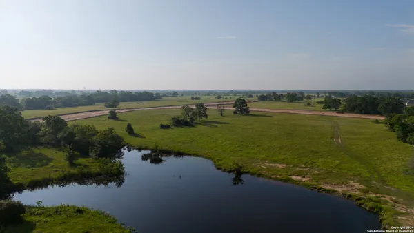 an aerial view of a houses with a yard and lake view