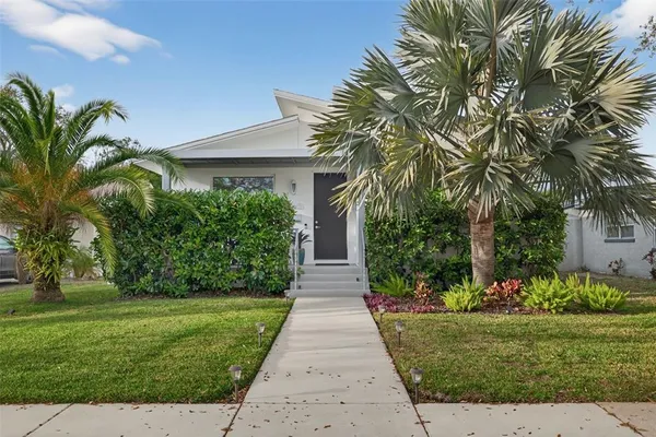 a front view of a house with a yard and potted plants