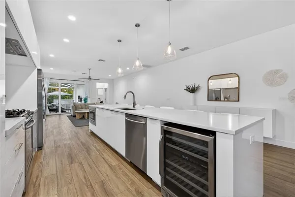 a large white kitchen with wooden floor and a sink