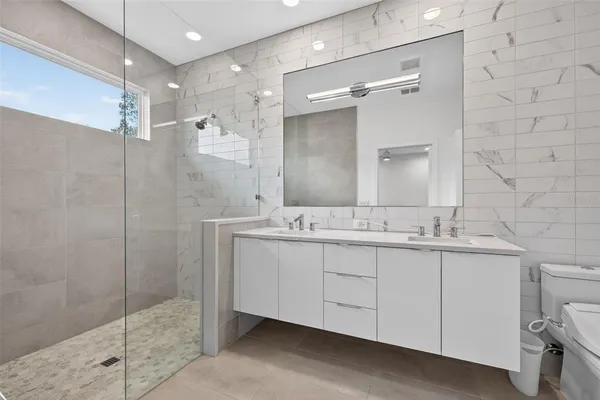 a bathroom with a double vanity sink mirror and shower