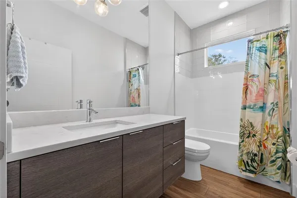 a bathroom with a granite countertop sink a toilet a mirror a vanity and shower