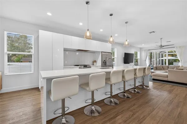 a large white kitchen with wooden floor and stainless steel appliances