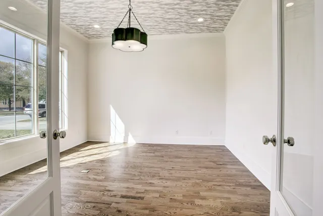 an empty room with wooden floor and windows