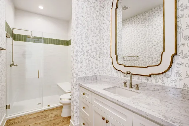 a bathroom with a granite countertop sink a toilet and shower