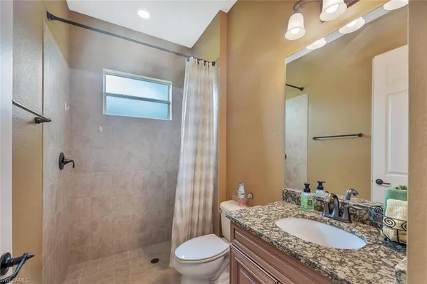a bathroom with a granite countertop sink toilet a mirror a vanity and shower