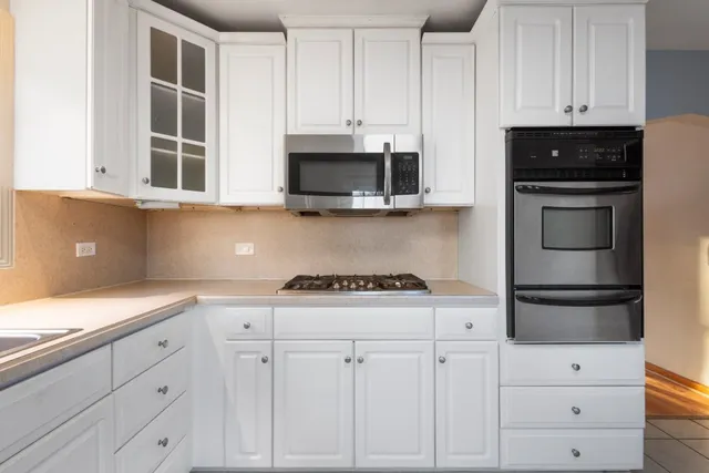 a kitchen with white cabinets and black appliances