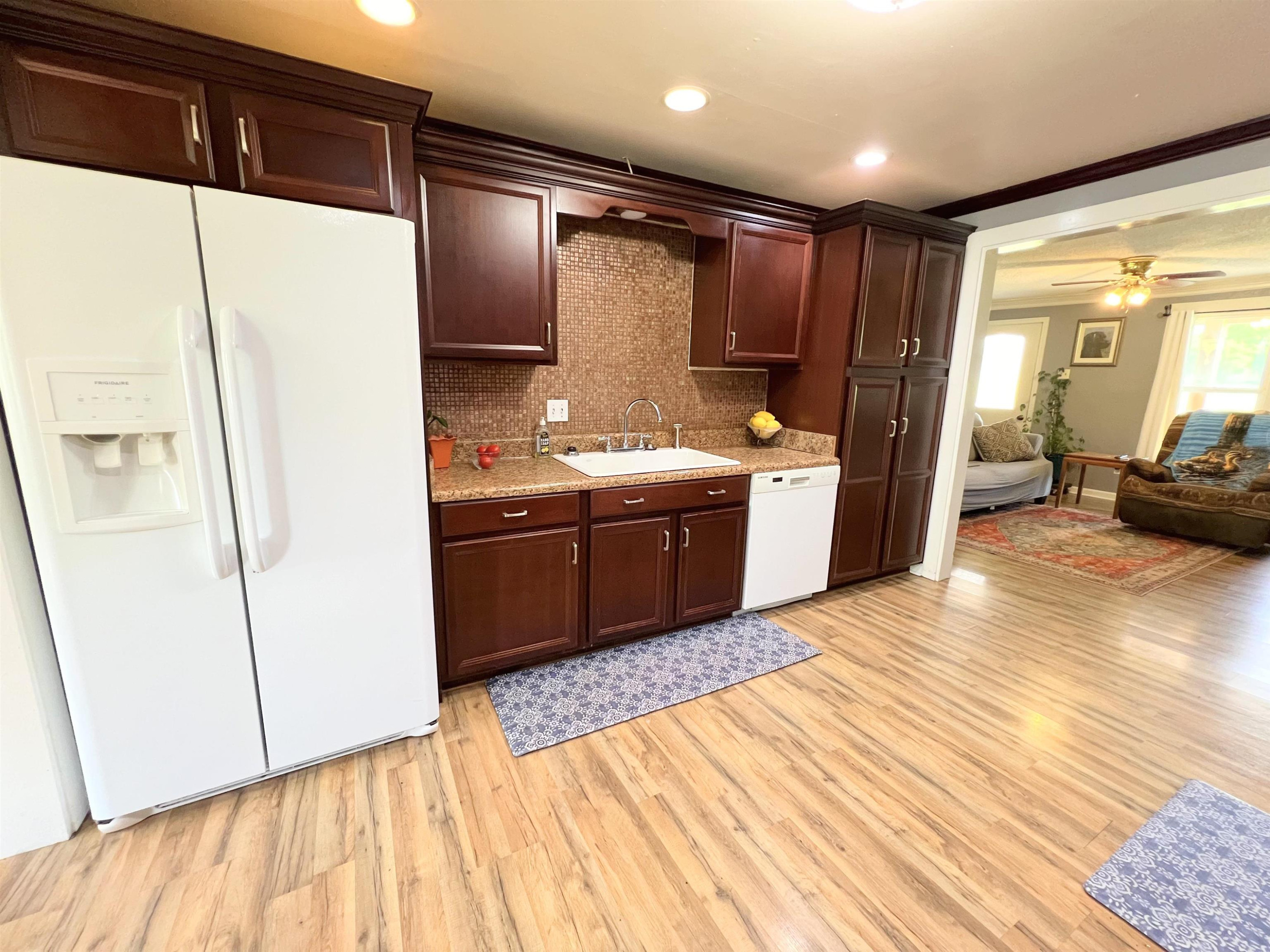 2390 Dr Lewis Road Ripley, TN 38063 - Photo 21 of 48 a kitchen with stainless steel appliances granite countertop a refrigerator a sink dishwasher and wooden cabinets with wooden floor