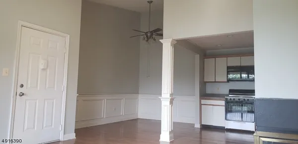 an empty room with wooden floor cabinet and windows