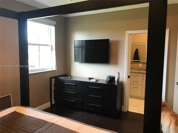 a bedroom with a bed and a flat tv screen on dresser