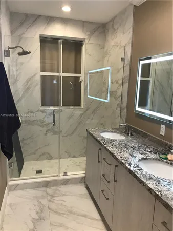 a bathroom with a granite countertop sink a mirror and shower