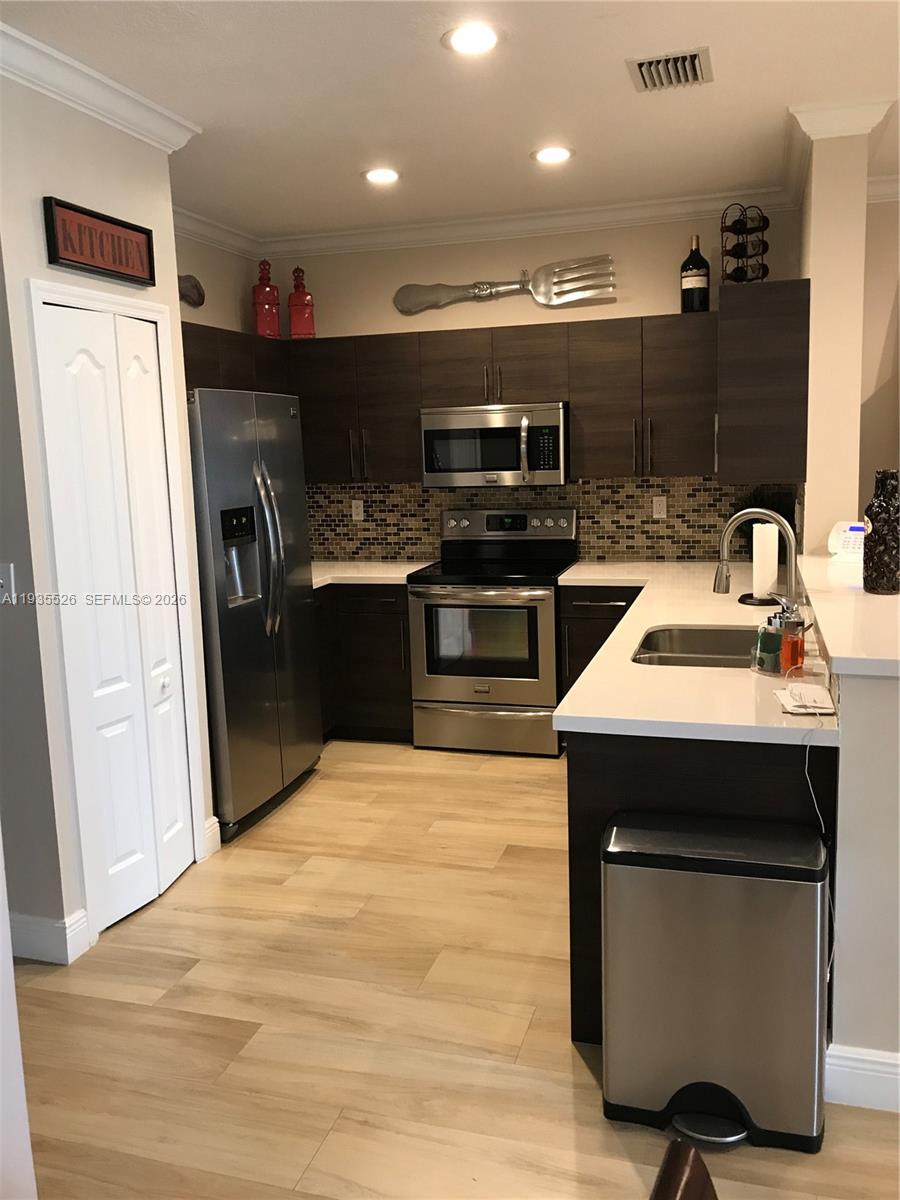 10872 Southwest 89th Street, Unit 10872 Miami, FL 33176 - Photo 6 of 25 a kitchen with kitchen island stainless steel appliances a sink wooden floor and refrigerator