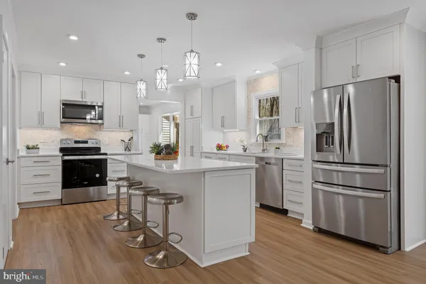 a kitchen with kitchen island white cabinets and stainless steel appliances