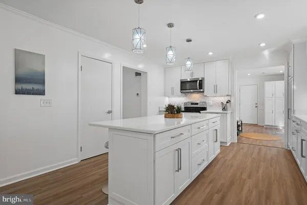 a large white kitchen with lots of counter space wooden floor and appliances