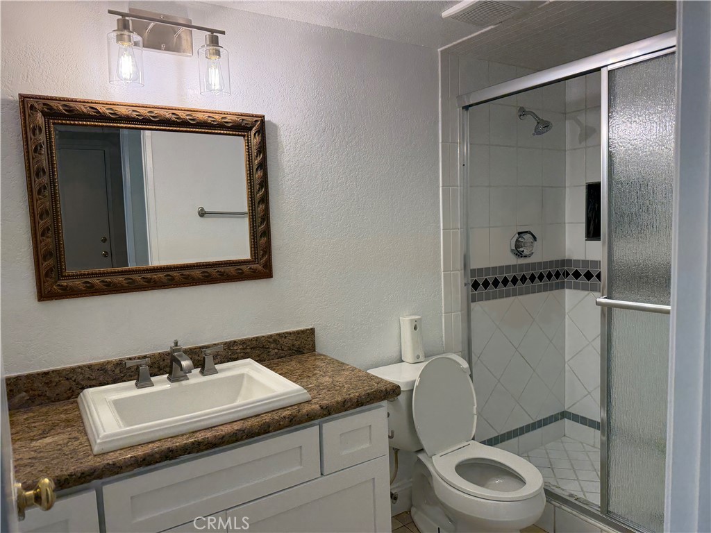2421 Mangular Avenue Corona, CA 92882 - Photo 12 of 25 a bathroom with a granite countertop toilet sink and mirror