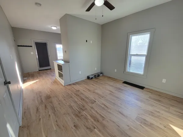 an empty room with wooden floor and windows