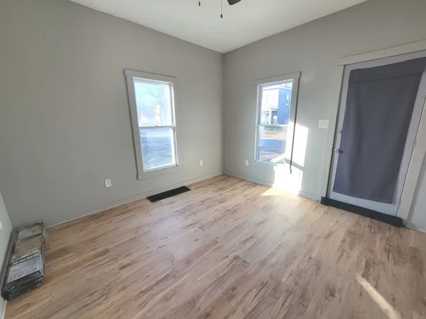 an empty room with wooden floor and windows