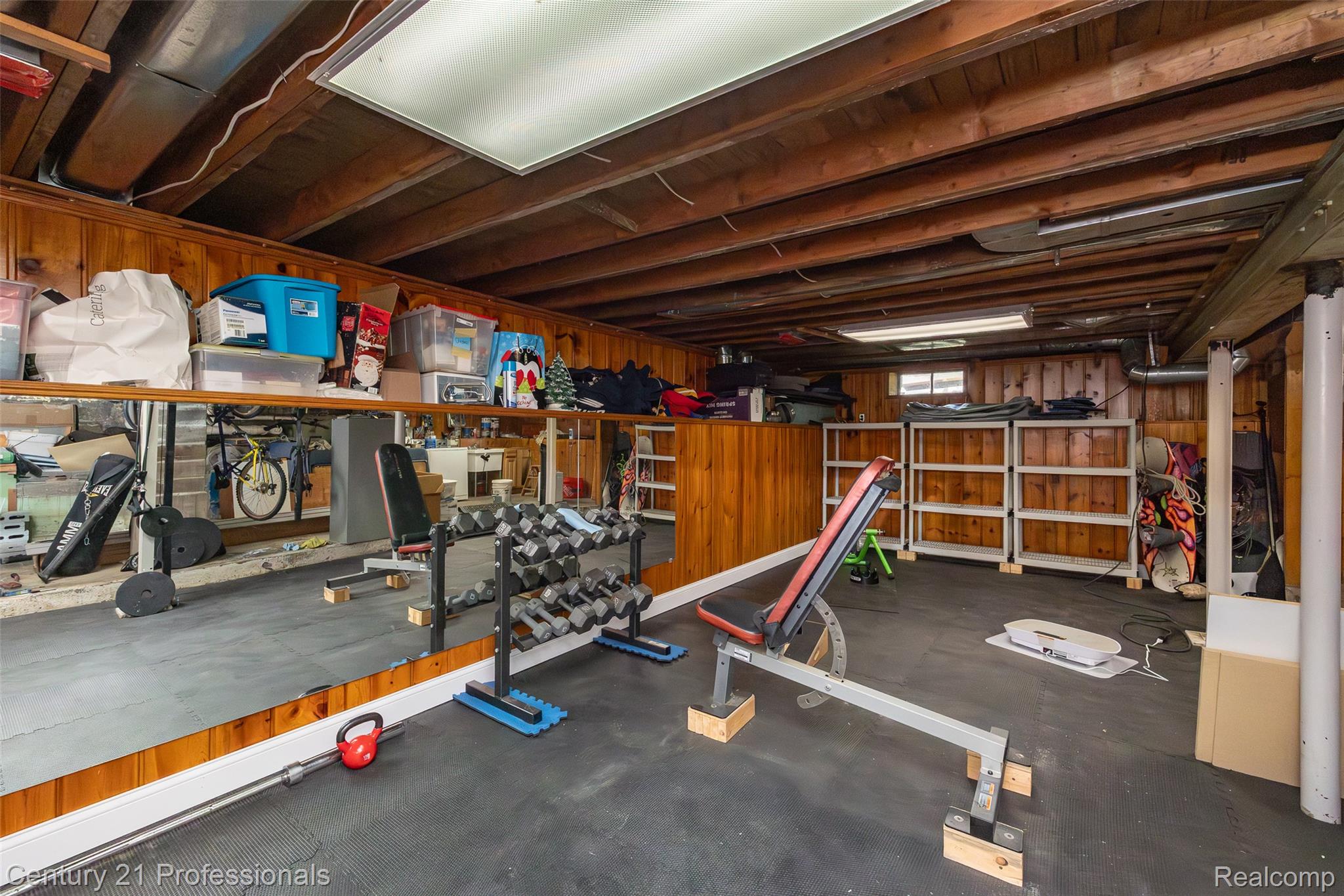 3251 Mann Road Clarkston, MI 48346 - Photo 34 of 40 Lower level space featuring exposed ceiling joists, wood paneling, and a large wall-mounted mirror