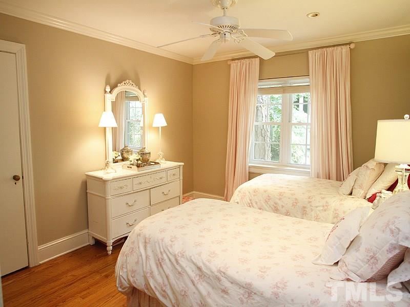 1307 Duplin Road Raleigh, NC 27607 - Photo 13 of 19 a bedroom with a bed a dresser and a large mirror with wooden floor