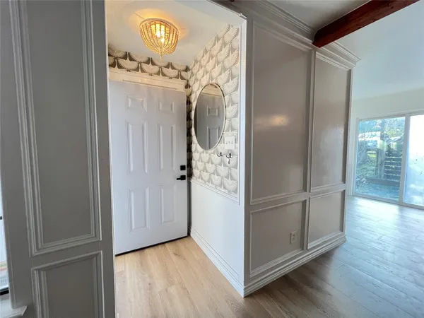 an empty room with wooden floor mirror and hallway