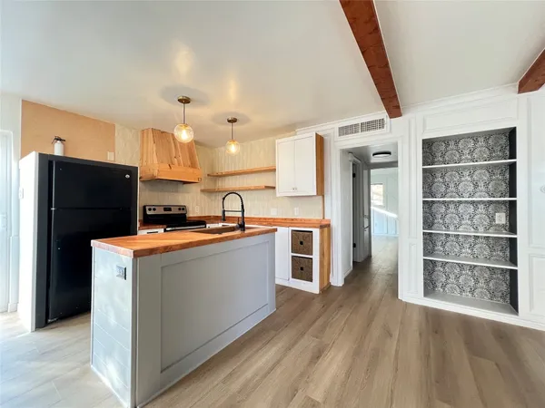 a kitchen with stainless steel appliances a refrigerator and a wooden floor