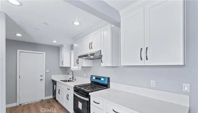 a kitchen with stainless steel appliances granite countertop a stove a sink and white cabinets
