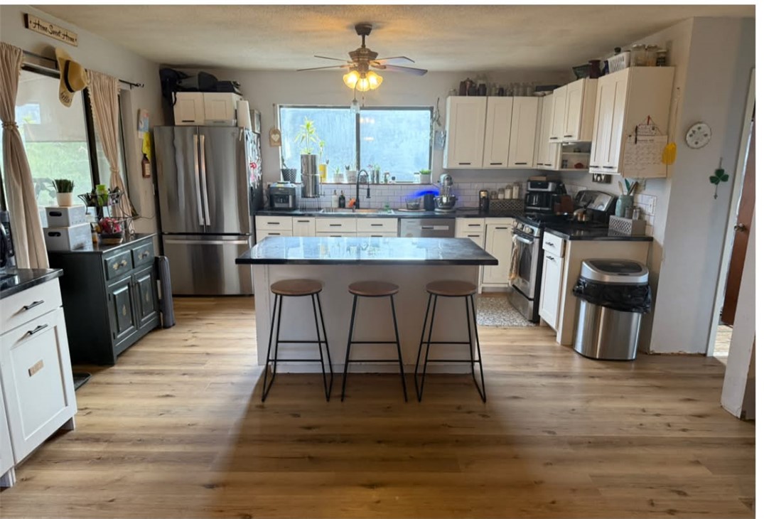 6233 Sunny Fox Road Mountain View, AR 72560 - Photo 5 of 26 White cabinetry, wood-finish flooring, central island with dark countertop, tiled backsplash, and ceiling fan