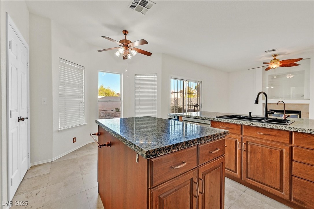 234 Highgate Street Henderson, NV 89074 - Photo 8 of 22 Kitchen with ceiling fan, brown cabinetry, a kitchen island, and dark stone countertops