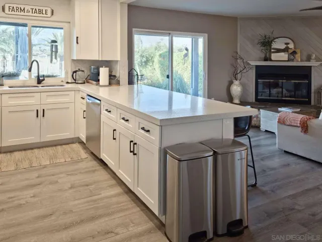 a kitchen with stainless steel appliances a sink a refrigerator and white cabinets