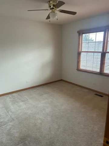 an empty room with a ceiling fan and window