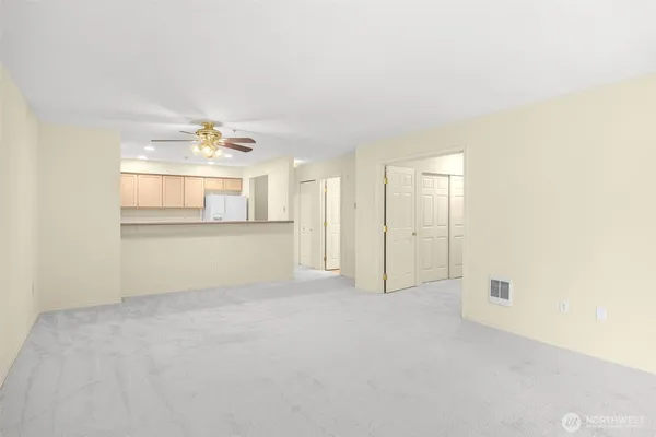 an empty room with windows and chandelier fan
